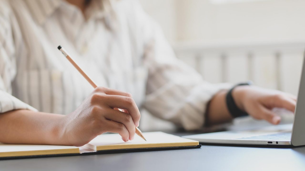 Una mujer tomando notas que lee en una notebook
